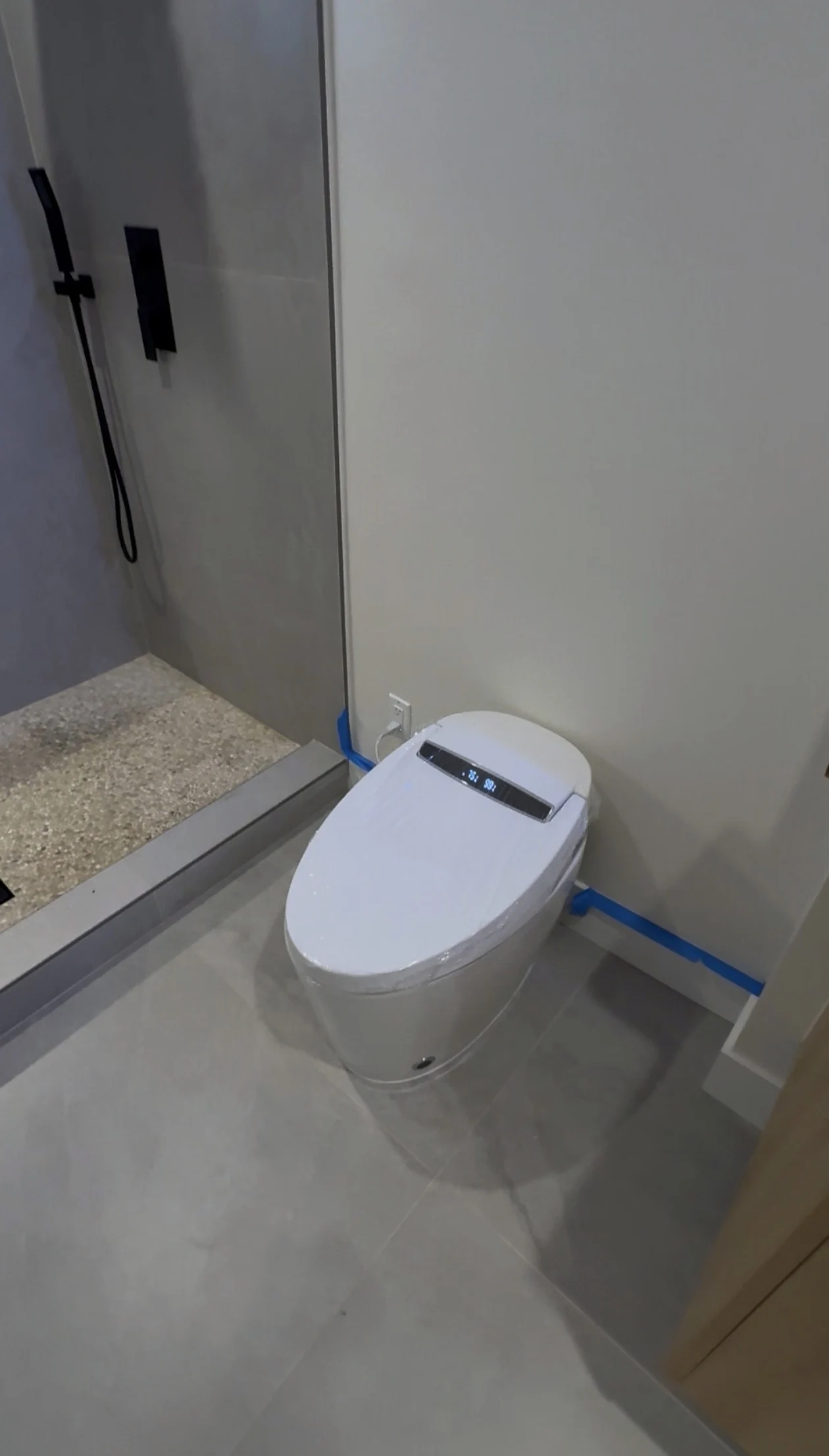 Bathroom tile, a pebble shower floor, black shower hardware and the toilet at the project walkthrough.